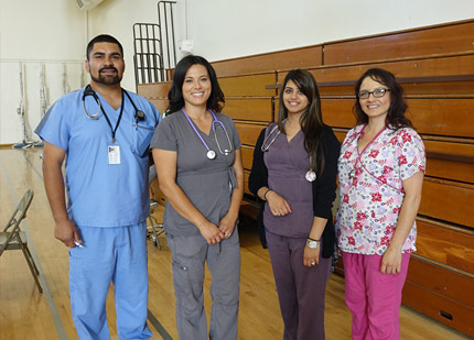 an image of four healthcare professionals standing together in an auditorium for a photograph in their scrubs