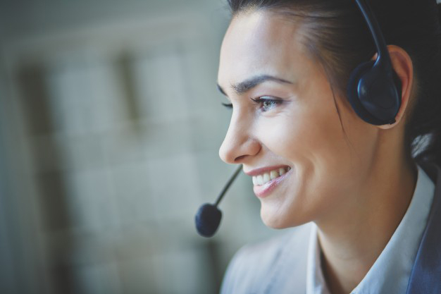 an image of a woman using a telephone headset while she happily talks with customers