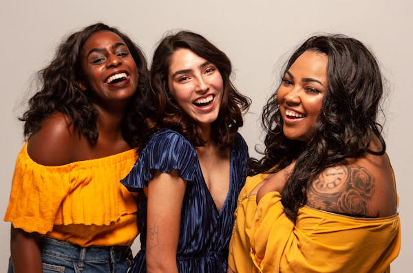 Three women standing next to each other and laughing