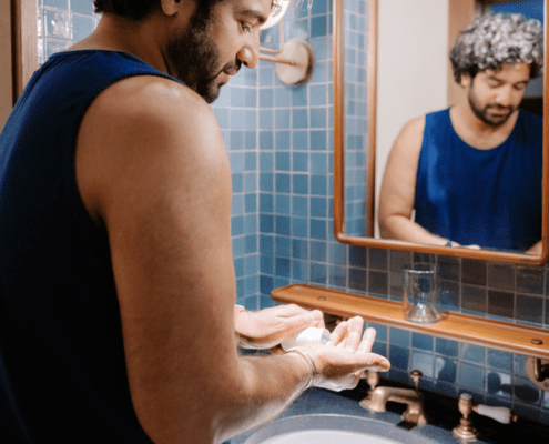 Man taking medication in front of a bathroom mirror