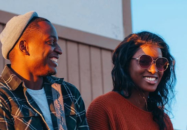 Two people of color sitting together outside and laughing