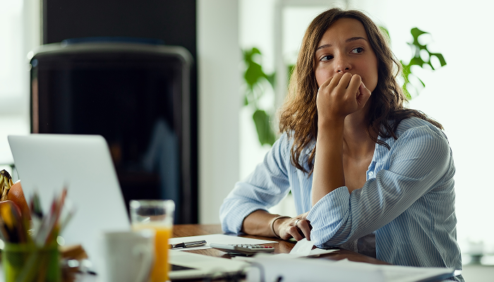 Woman sitting at a desk looking over her shoulder with a hand on her chin