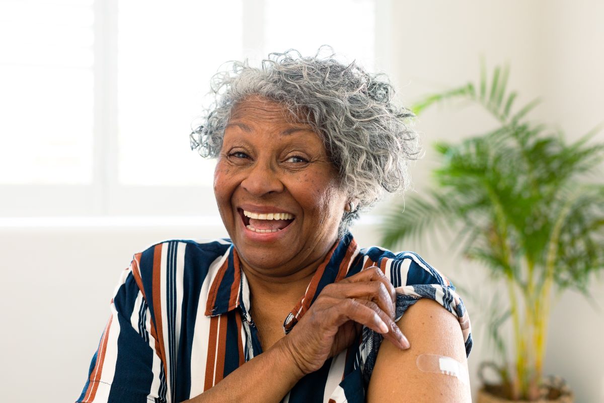 Elderly woman lifting her sleeve to show where a vaccine was received.