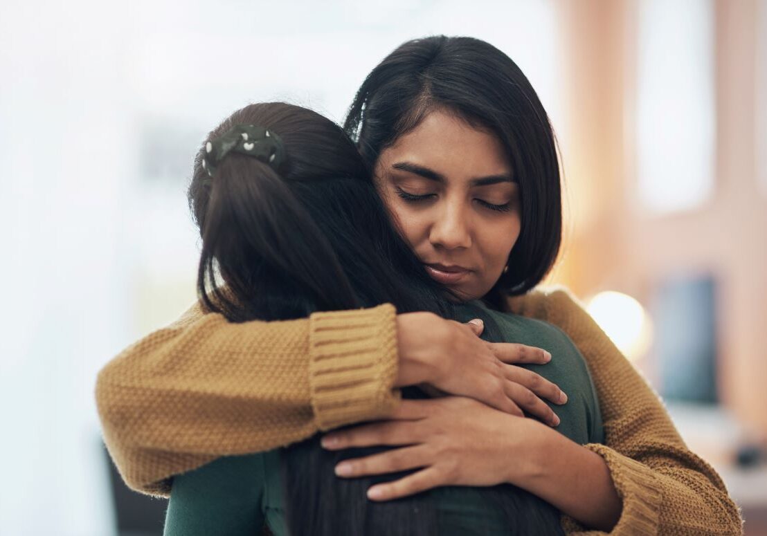 Two people hugging each other in support