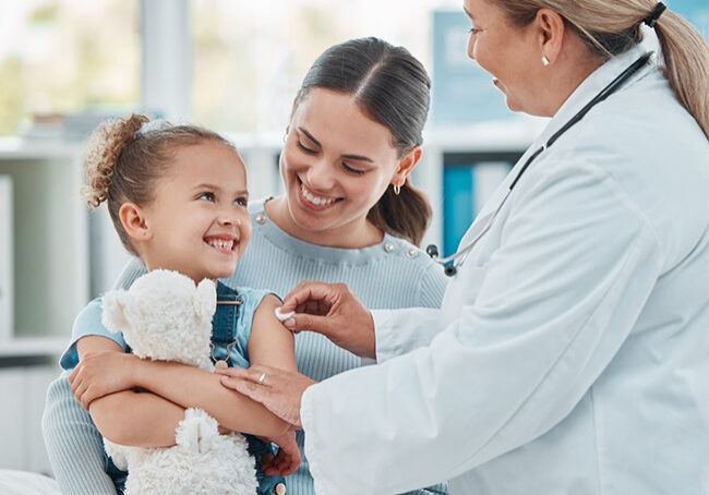 Doctor holding a stethoscope on a pediatric patient that is being held by a parent